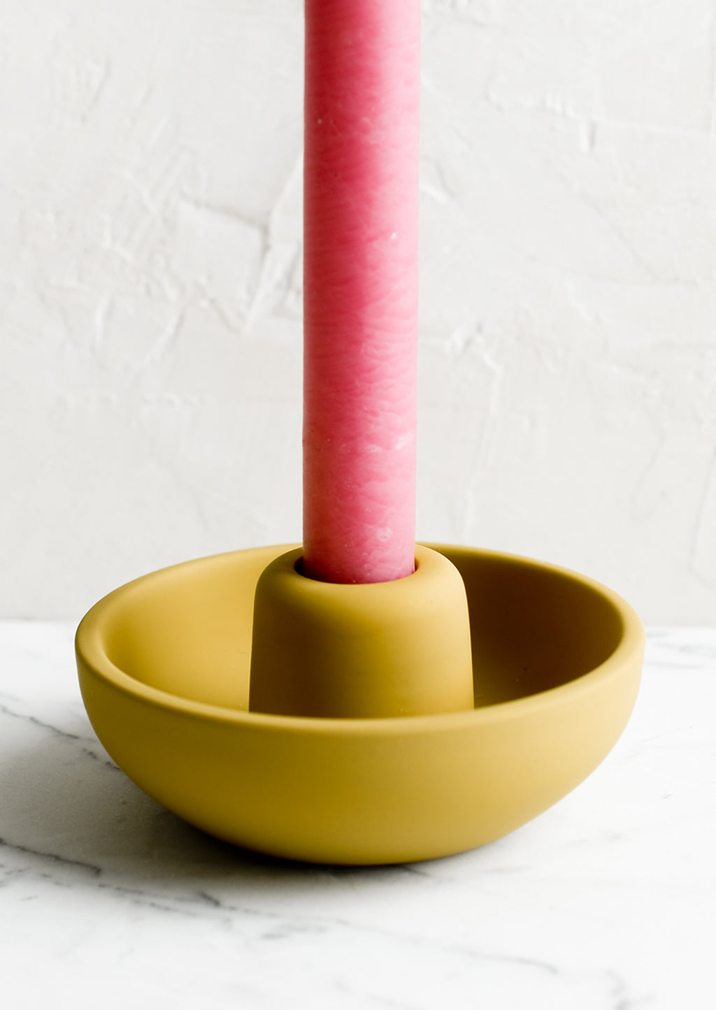 Mustard: A matte taper candle holder with bowl-like base in mustard with pink candle.