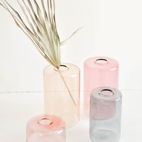 4: An assortment of colored glass flower vases shown with decorative palm leaf