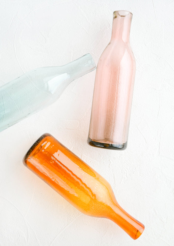 Wine-bottle shaped glass bottles in tinted hues of pink, orange and blue