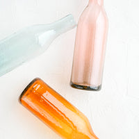 1: Wine-bottle shaped glass bottles in tinted hues of pink, orange and blue
