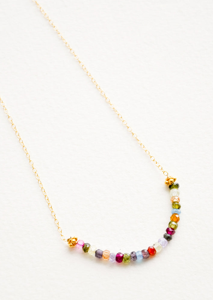 Yellow gold chain necklace with multicolored glass beads arranged in a half circle.