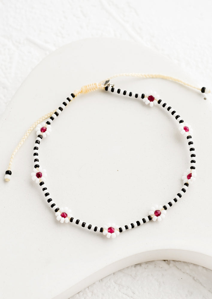 A beaded bracelet in black and white with burgundy flowers.