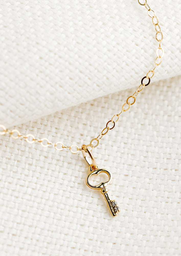 A gold necklace with tiny key charm.