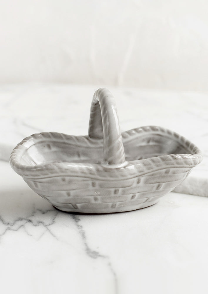 A grey ceramic dish in the shape of a picnic like basket.