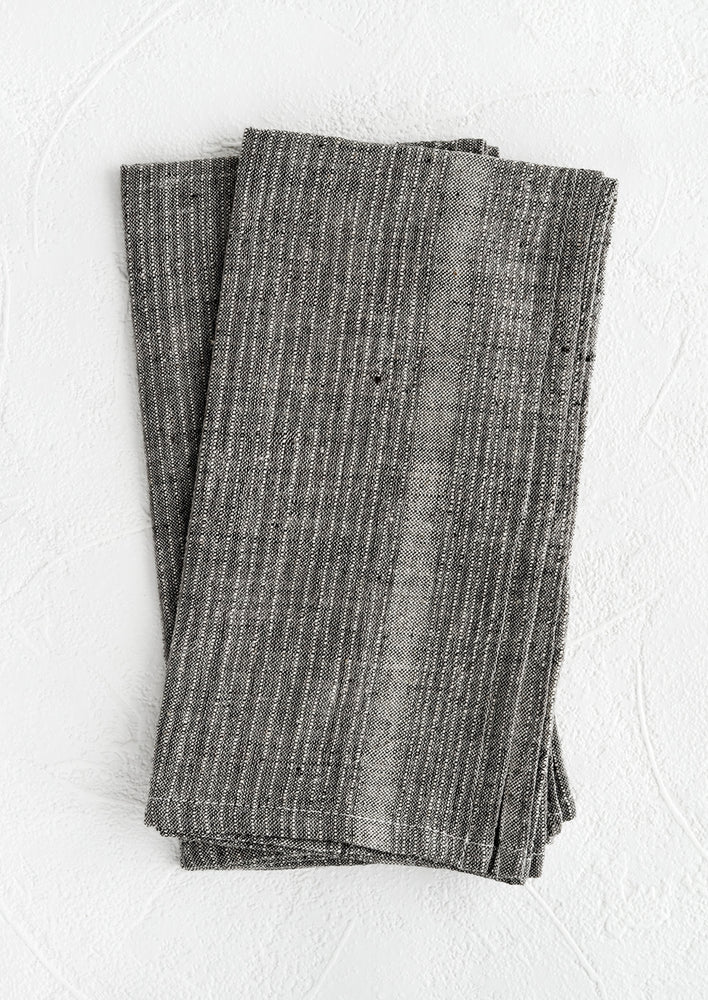 A pair of charcoal fabric napkins with textured tonal stripe pattern.