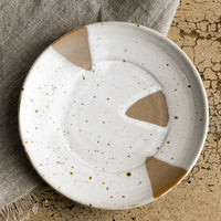 1: A small round saucer-like plate with brown and white triangle design.