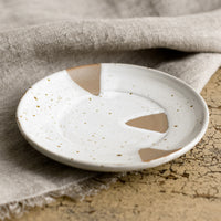 2: A small round saucer-like plate with brown and white triangle design.