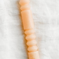 Pomelo: A geometric shape taper candle in pomelo (peach).