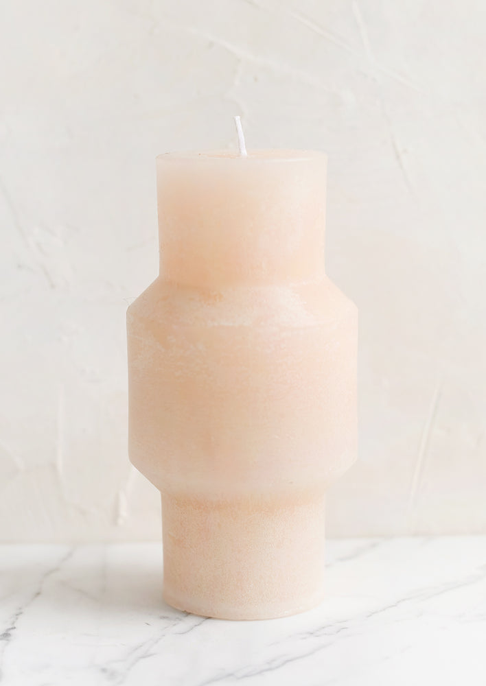 A medium carved pillar candle with waxy finish in petal.