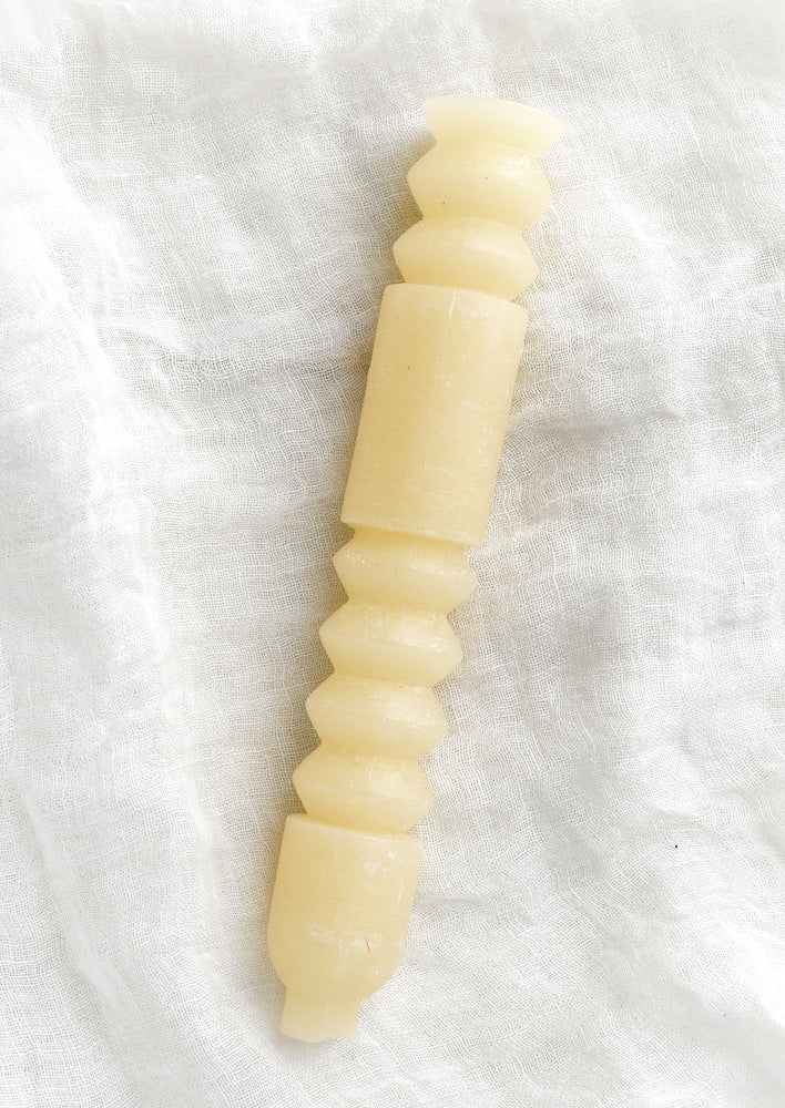 A geometric shape taper candle in vanilla (off white).