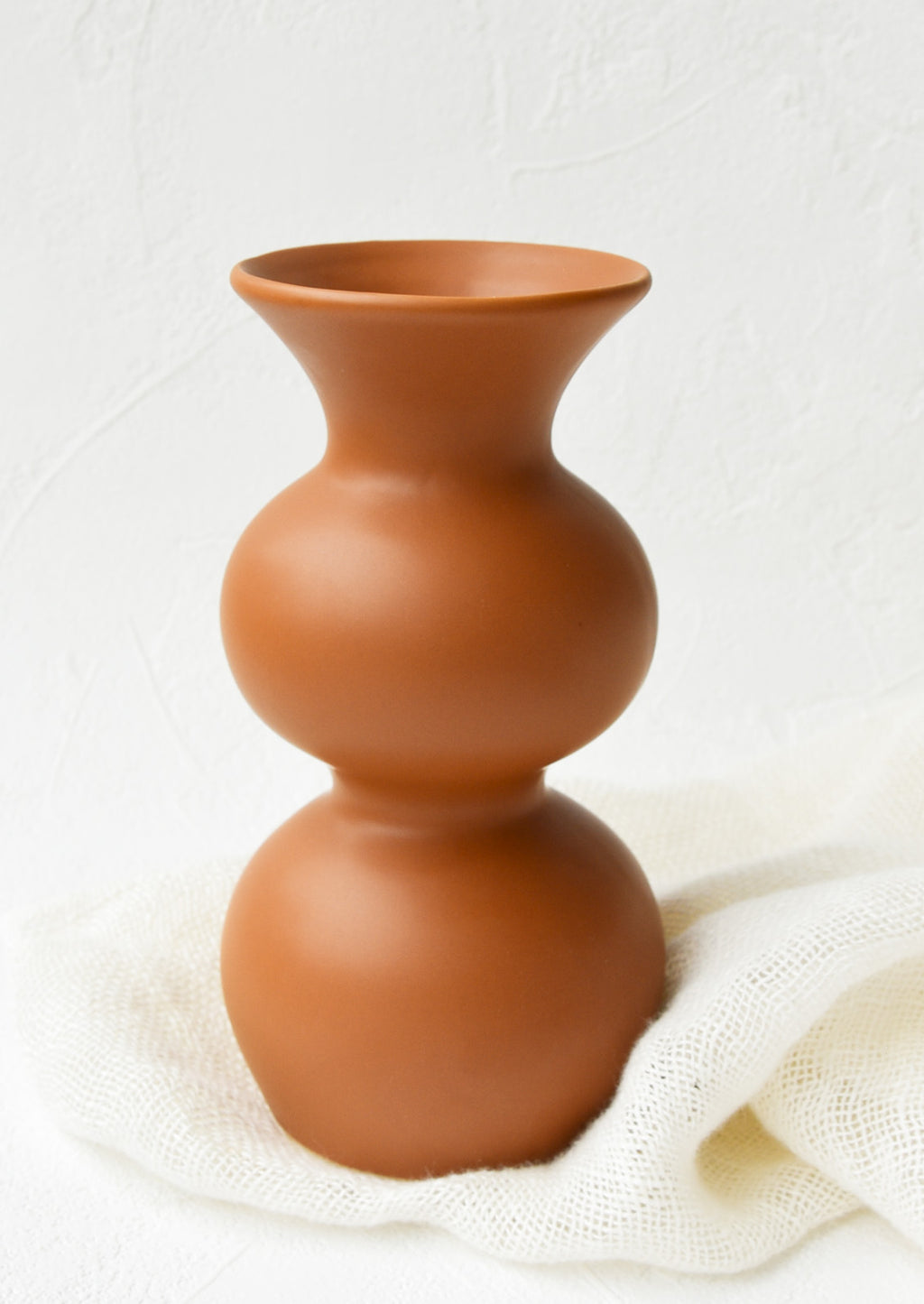 1: An hourglass shaped vase in a terracotta colored glaze