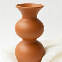 1: An hourglass shaped vase in a terracotta colored glaze