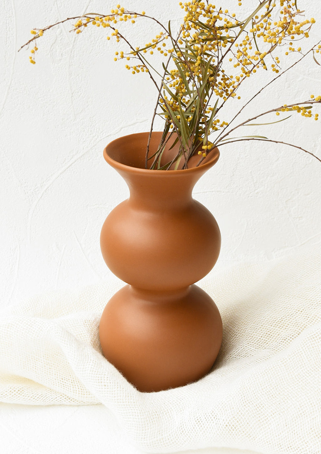 2: An hourglass shaped vase in terracotta filled with yellow flowers