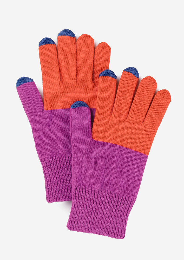A colorblock pair of knit yarn gloves in orchid and poppy with navy blue tips.
