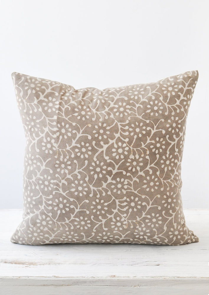 A grey and white floral block-printed square pillow.