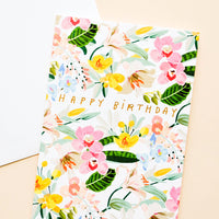 1: Greeting card with bright white floral background and gold lettering reading "Happy Birthday"