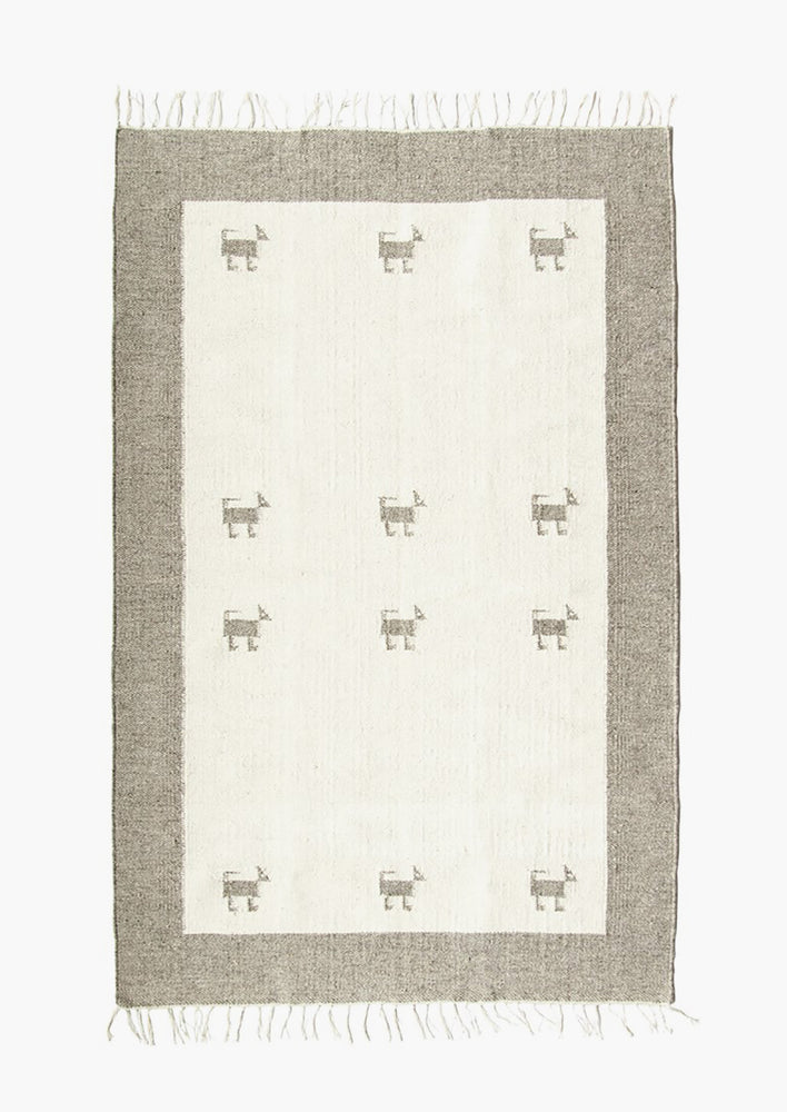 A wool rug with contrast border and light center with dog icons.