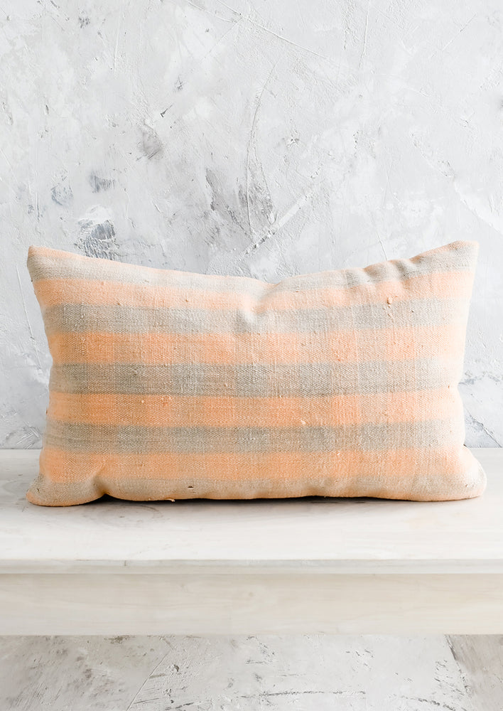 A lumbar kilim throw pillow in peach and grey gingham.