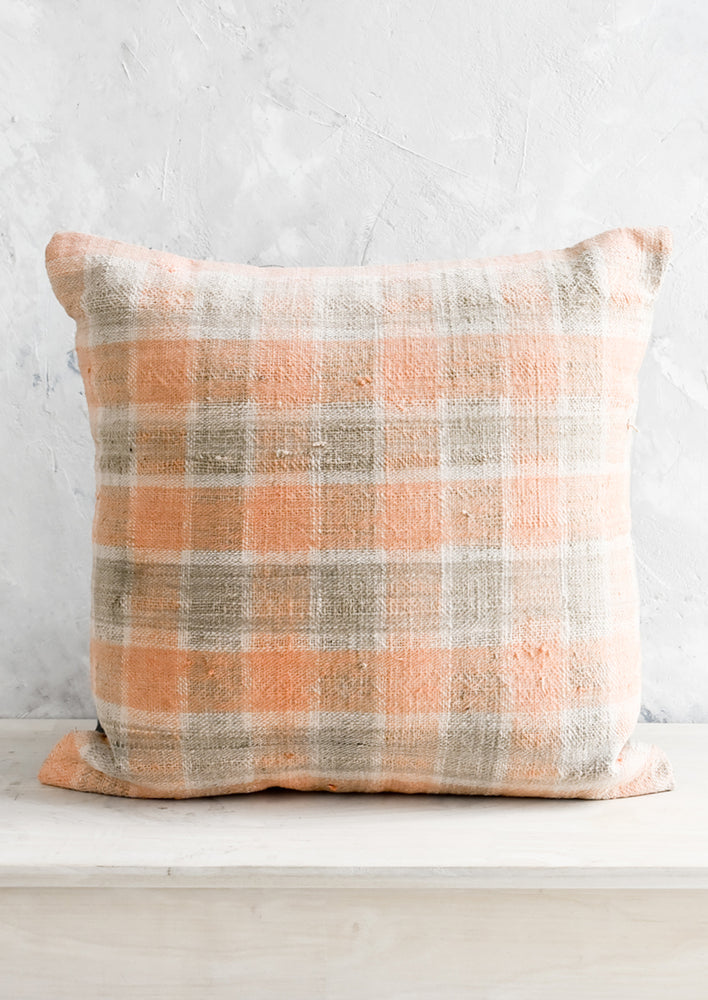 A square kilim throw pillow in peach and grey gingham.