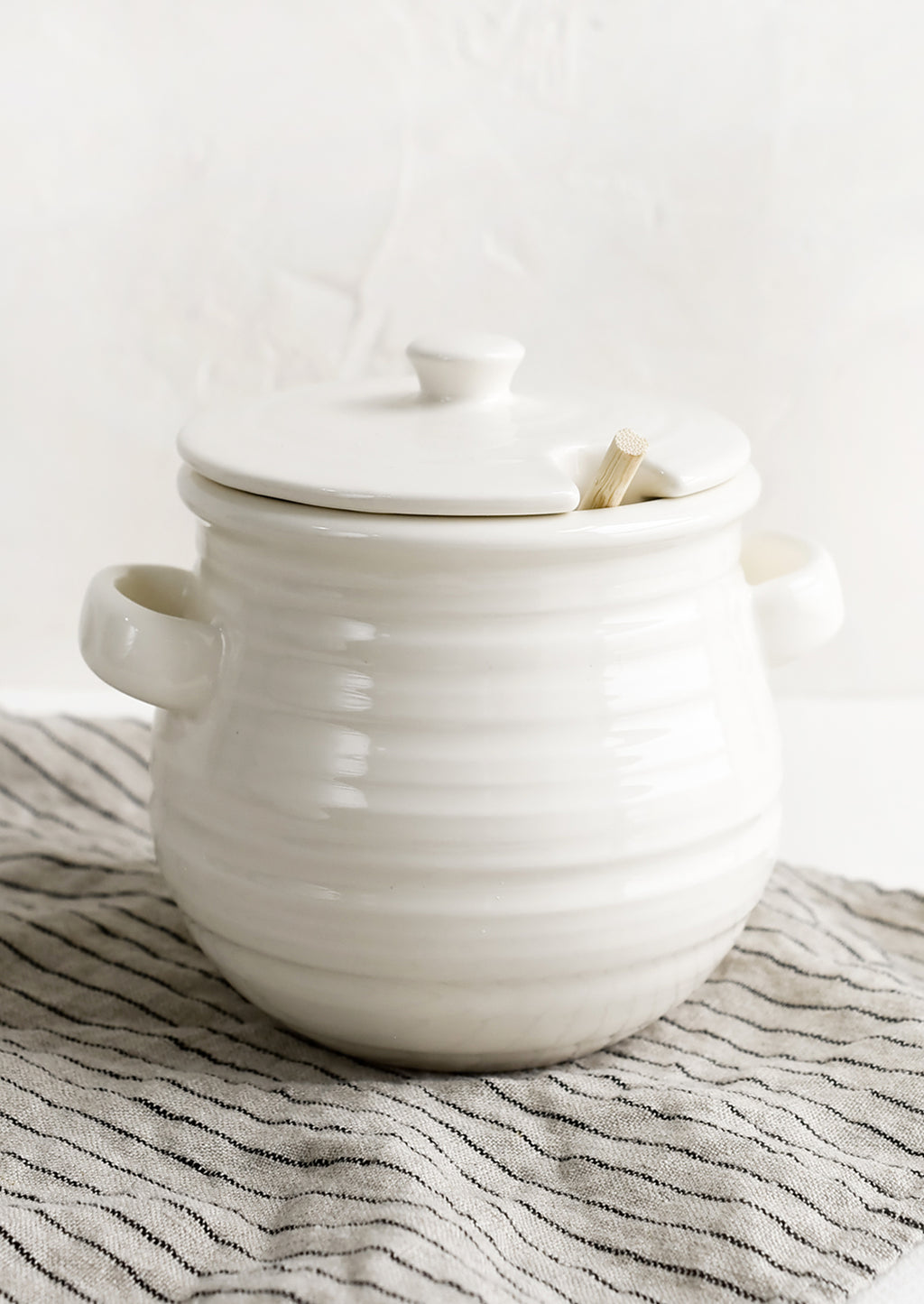 1: A glossy white ceramic honey jar with side handles and lid.