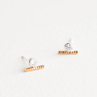1: Stud earrings with a round white crystal set in a silver, attached to a short textured gold bar.