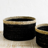 1: A shallow circular basket in black with tan rim, in small and medium sizes.