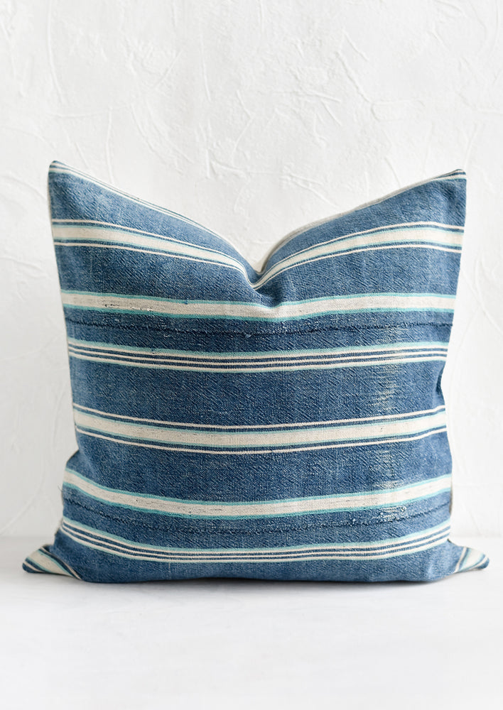 A square throw pillow in vintage indigo stripe fabric.