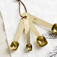 1: A set of four golden measuring spoons with brown leather tie.