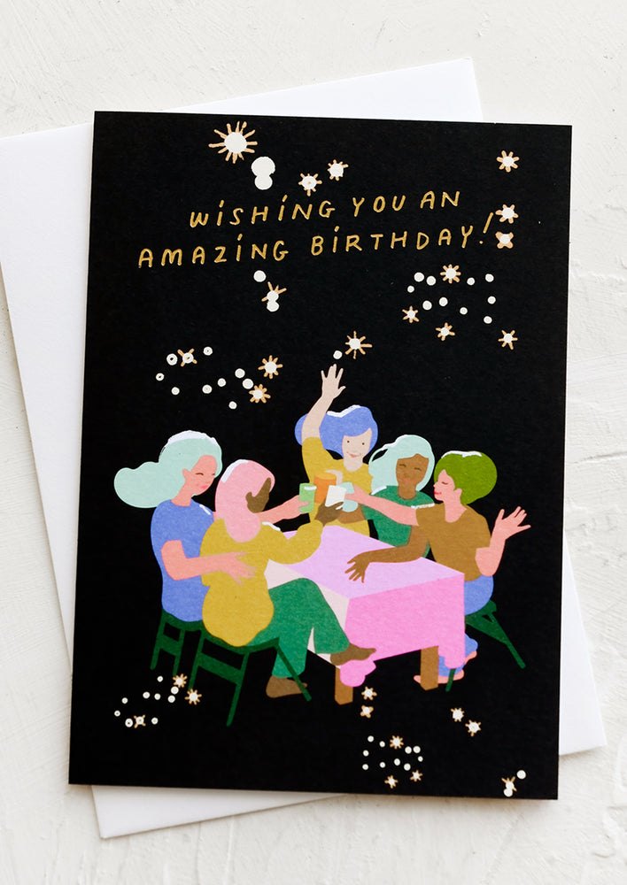 A card with illustration of women partying at a table under the stars, text reads "Wishing you an amazing birthday!".