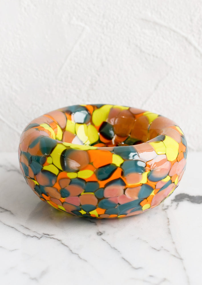 A speckled multicolor glass bowl in teal, peach, orange and yellow.