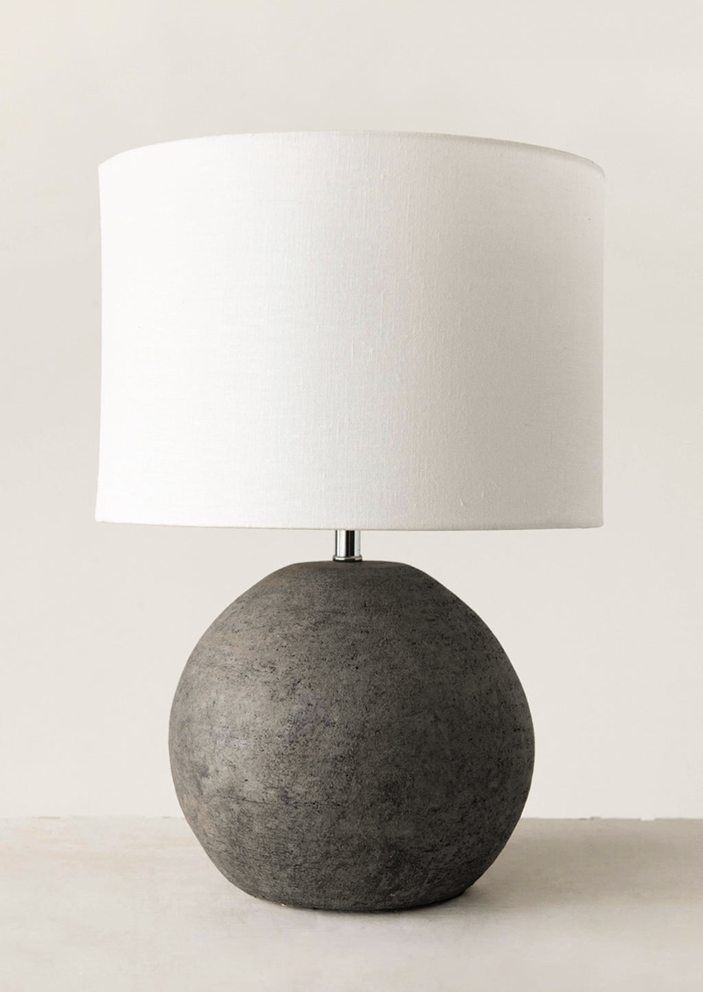 1: A table lamp with round black terracotta base and white cylinder shade.