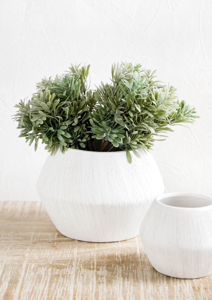 Reverse hourglass shaped planters in small and large size. White ceramic with allover fine line texture.
