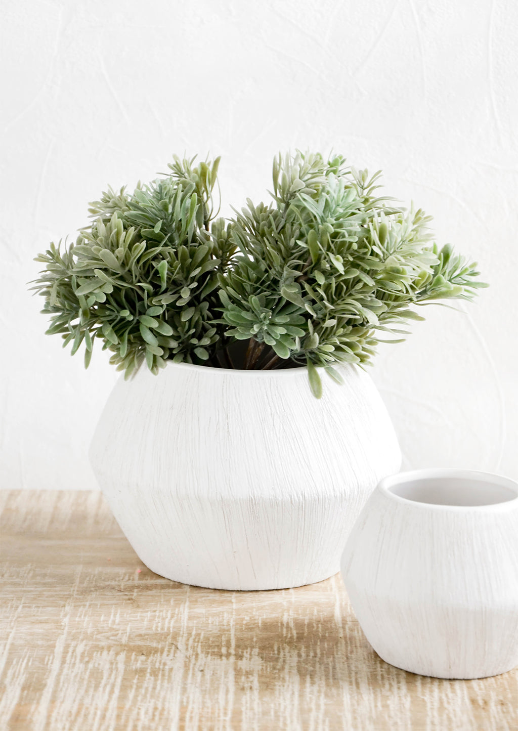 1: Reverse hourglass shaped planters in small and large size. White ceramic with allover fine line texture.