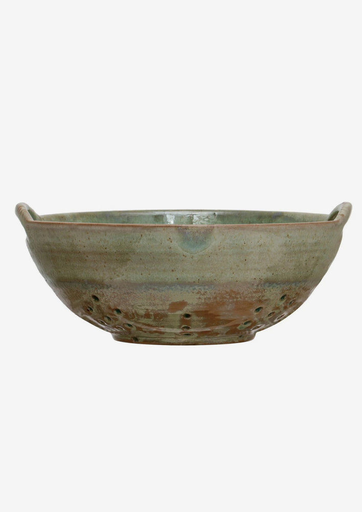 A large ceramic colander in mottled aqua glaze.