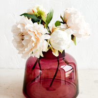 1: A berry colored glass vase with peonies.