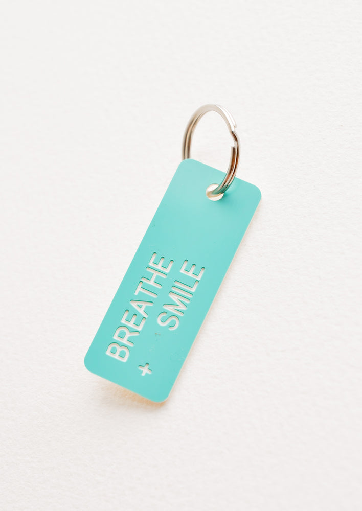 Breathe + Smile: Small acrylic keychain, turquoise background with white words that says "BREATHE + SMILE"