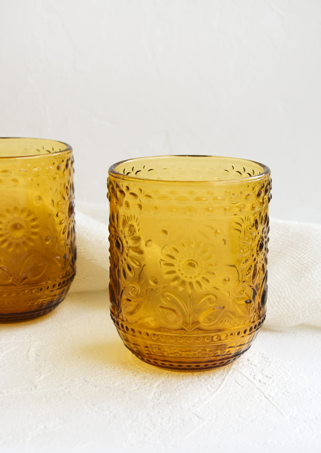 Amber: Two amber glass tumblers with floral embossed motif.