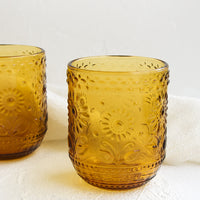 Amber: Two amber glass tumblers with floral embossed motif.