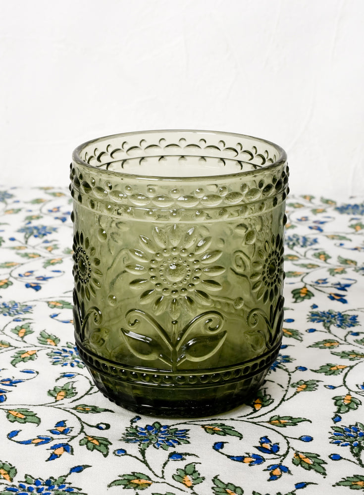 An olive green glass tumbler with floral embossed motif.