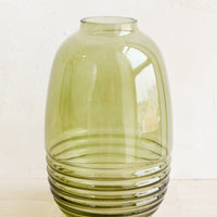 1: A tall curvy green glass vase with narrow mouth and ribbing detail at bottom.