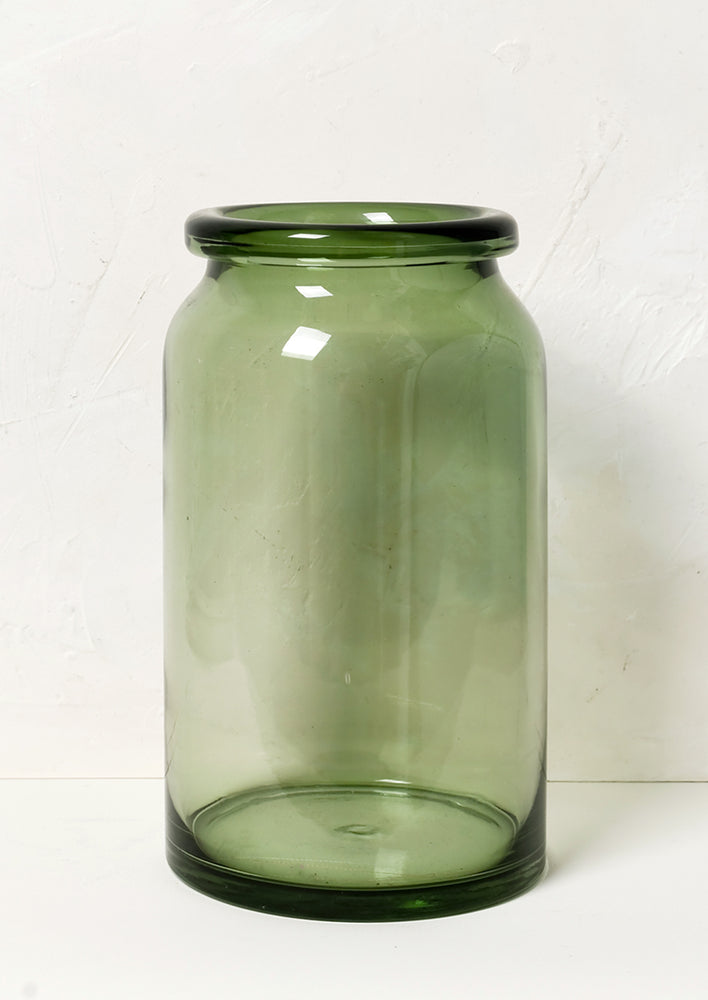A tall, clear green glass vase with rolled rim.