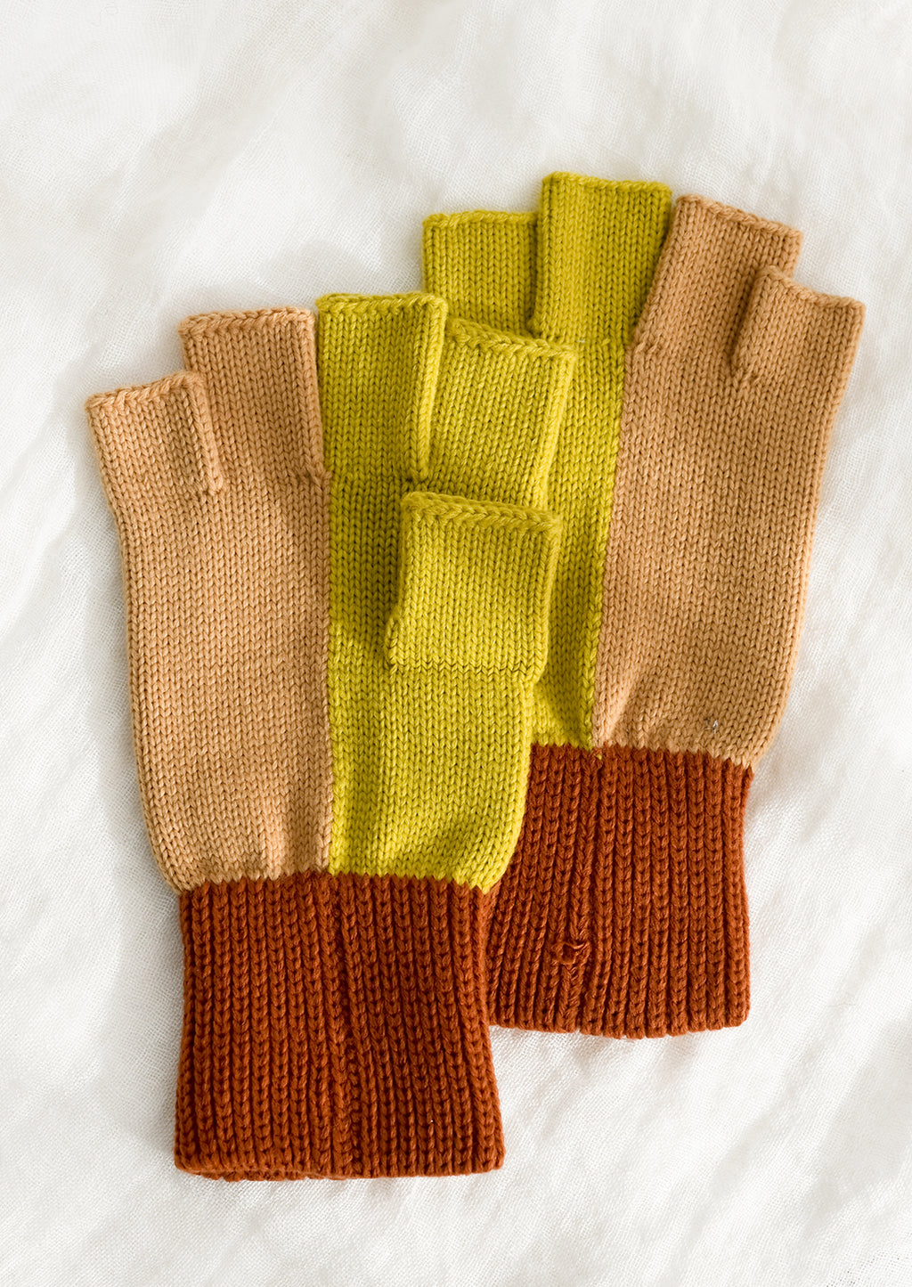 Citrine Colorblock: A pair of knit fingerless gloves in terracotta, peach and citrine colorblock.