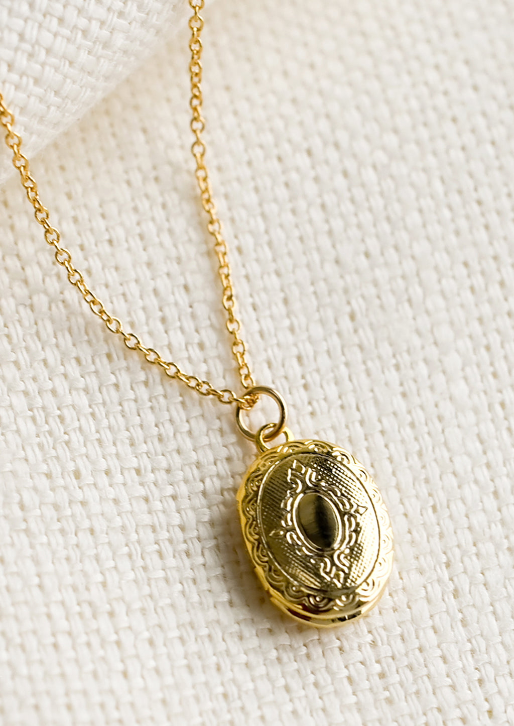 1: A oval shaped locket necklace with antique inspired engraving.