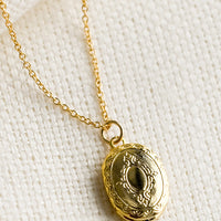 1: A oval shaped locket necklace with antique inspired engraving.