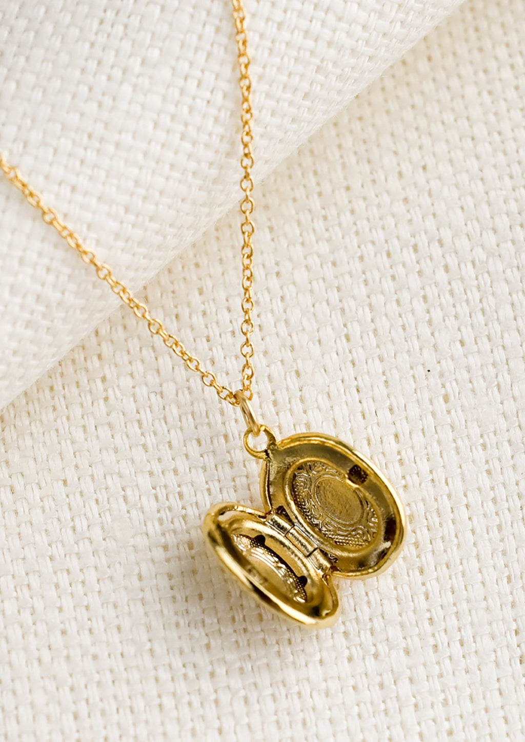 2: A oval shaped locket necklace with antique inspired engraving.