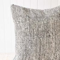 2: A black and white woven pillow with wavy lines.