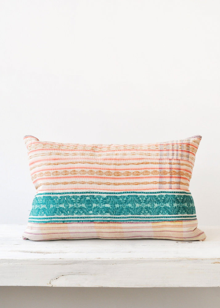A multicolored pillow made of vintage quilt fabric.