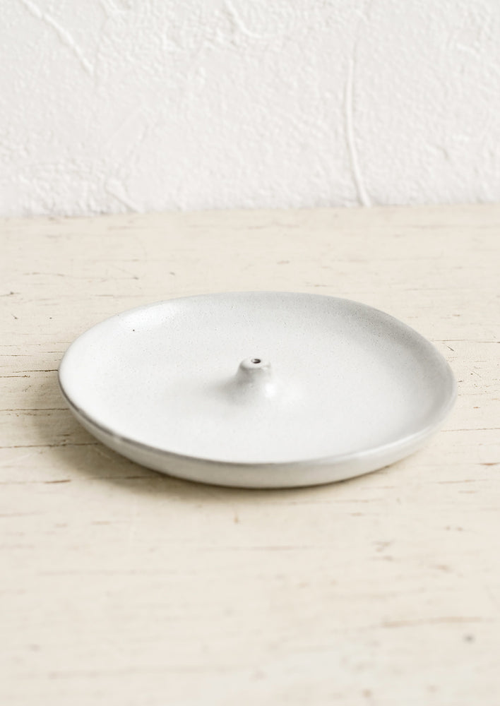 A subtly asymmetrical round ceramic incense holder.
