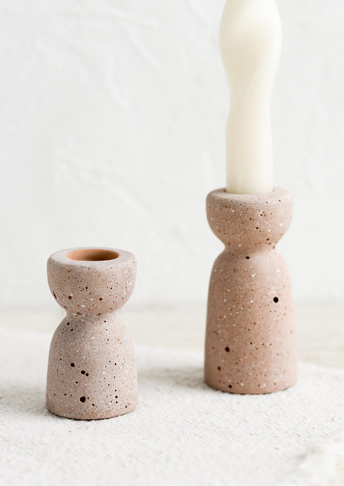 Two short and tall brown-pink concrete candleholders with pumice-like texture.