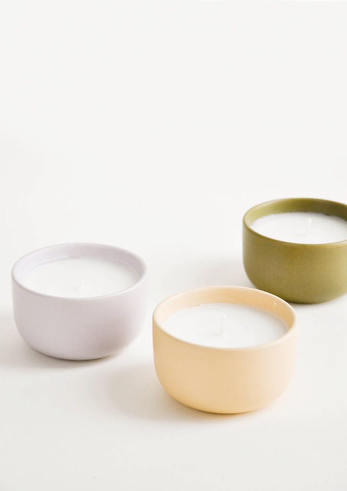 Small scented candles in colorful ceramic vessels